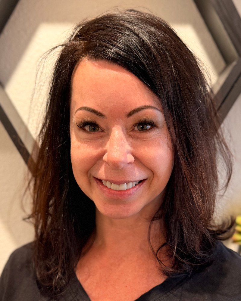 Shannon, experienced dental hygienist, smiling warmly in dark scrubs at the dental office